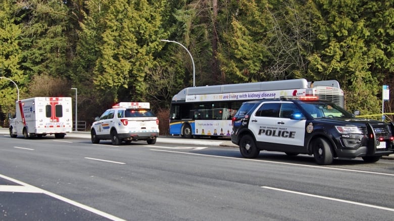 A bus is pictured parked on the side of the road, with police and emergency vehicles blocking the road on all sides.