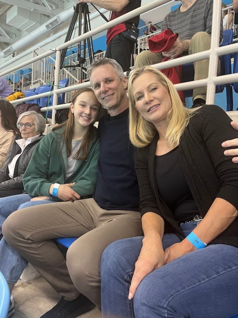 A man sits in between two women with his arms around their shoulders.