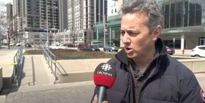 A man speaks into a microphone outside. 