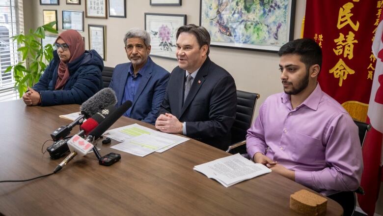 Four people sit at a  table ready to speak to the media. An Egyptian husband and wife sit next to a white male politician who is flanked on the other side by an Egyptian activist.