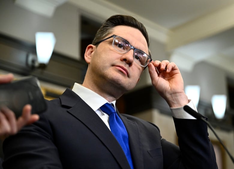 Conservative Leader Pierre Poilievre adjusts his glasses as speaks to reporters after the tabling of the Federal Budget in the in the House of Commons on Parliament Hill in Ottawa, on Tuesday, March 28, 2023.