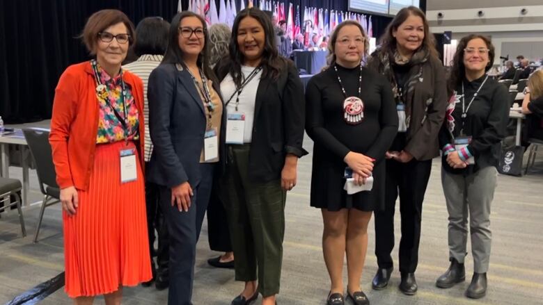 Six women stand in a row the AFN assembly.