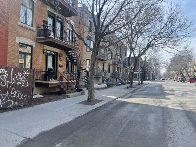 A residential street with trees and dwellings. 