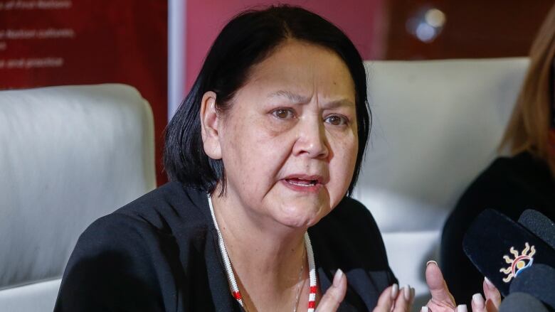 A woman seated in front of microphones.