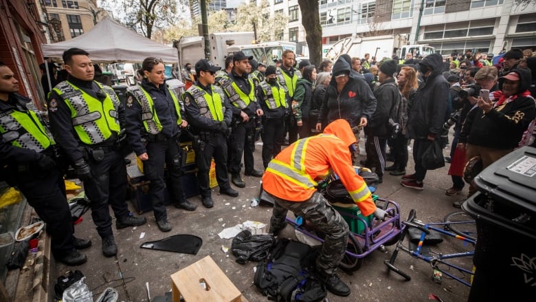 VPD officers form a line to push back protesters and advocates while city employees work to dismantle tents along East Hastings in the downtown Eastside neighbourhood of Vancouver, British Columbia on Wednesday, April 5, 2023. 