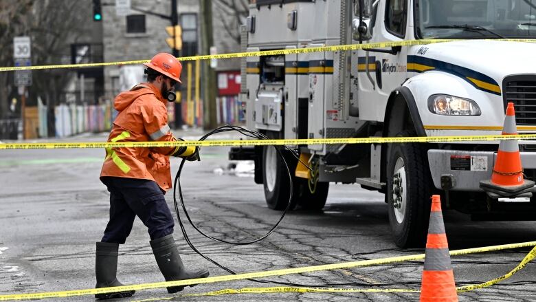 A Hydro Ottawa worker coils up a line that was taken down by a fallen tree branch in Wednesday's major ice storm, in Ottawa, on Thursday, April 6, 2023.