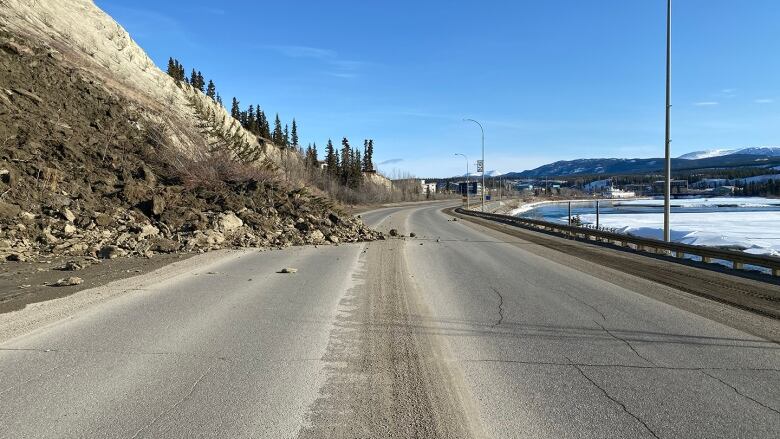 The photo shows a portion of the road covered with rocks and mud after a landslide