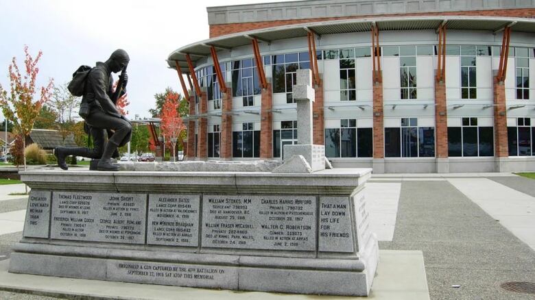 A bronze statue of a soldier with a gun is pictured atop a cenotaph, with various names inscribed on it.