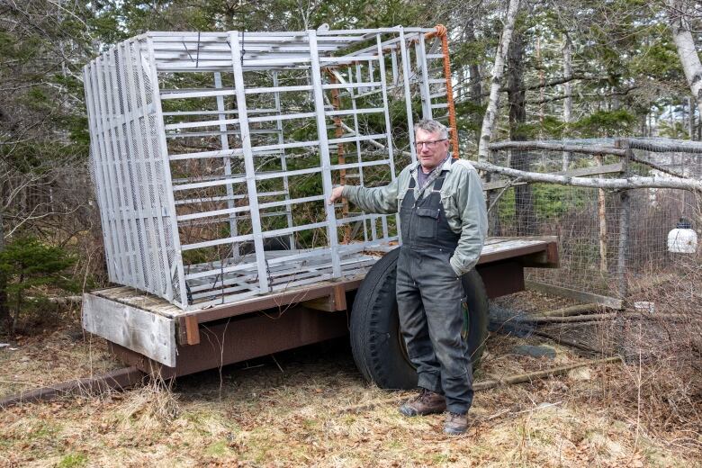 A man stands next to a metal shark cage.