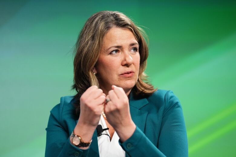 A woman is pictured in front of a green backdrop.