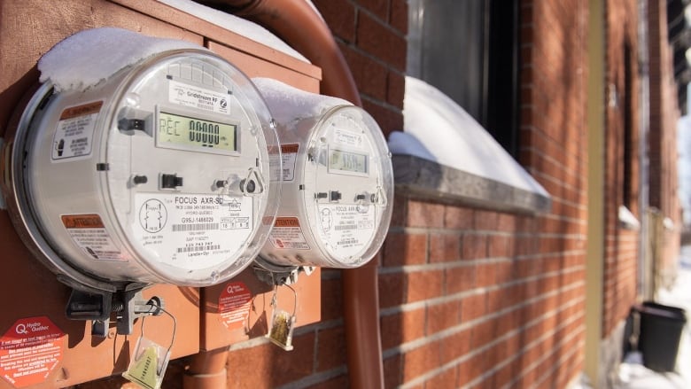 Electricity meters are shown on the side of homes in Montreal on February 4, 2023. 