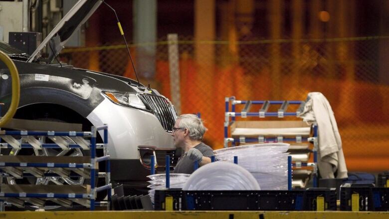 A line worker works on a car at Ford Motor plant in Oakville, Ont., on Friday, January 4, 2013.