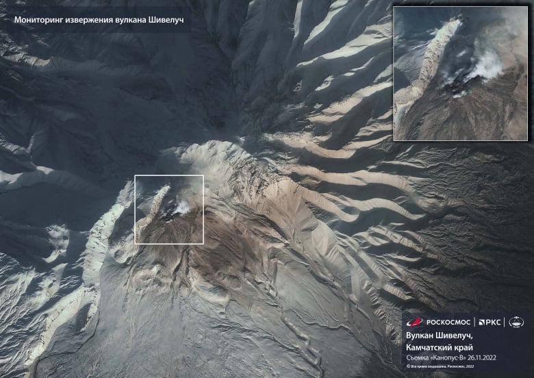 A satellite image of a volcano with a plume of smoke coming out of the lower left peak. 