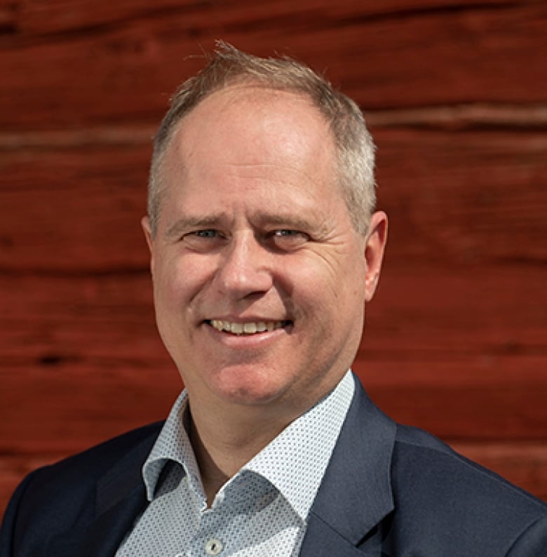 Portrait of Martin Forsn's face. He is wearing a dark jacket and a collared shirt with a white and light blue pattern.