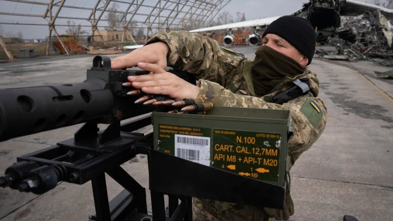 A Ukrainian soldier of a mobile air defence unit demonstrates his skills at the Antonov airport as the gutted remains of the Antonov An-225, the world's biggest cargo aircraft, destroyed during fighting between Russian and Ukrainian forces, are seen in the background, in Hostomel, on the outskirts of Kyiv, Ukraine, Saturday, April 1, 2023.