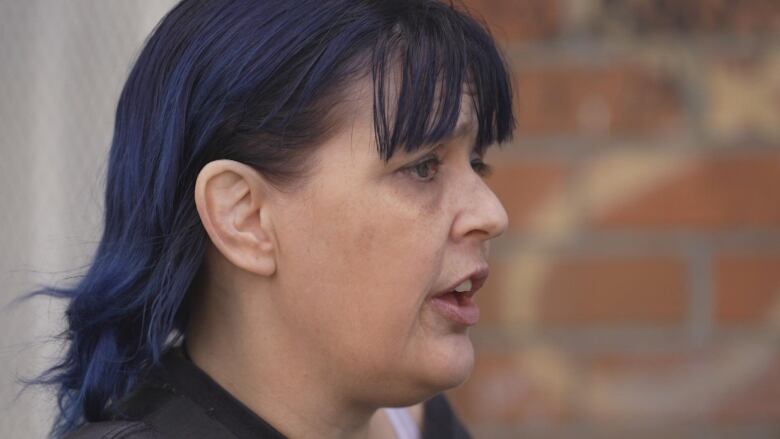 A woman with blue hair is pictured in profile.