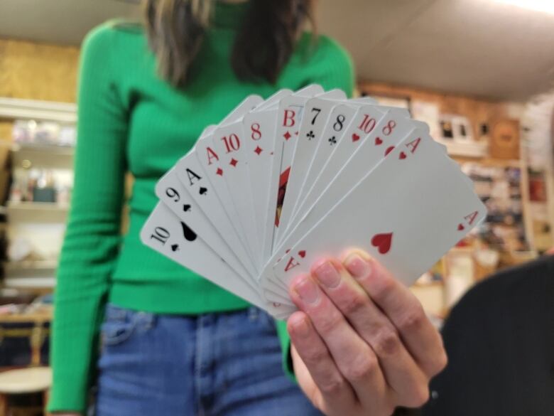 An Edmonton skat player holds up a deck of cards.