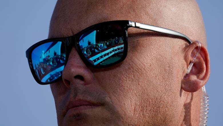 Supporters of President Donald Trump are reflected in the glasses of a U.S. Secret Service agent during a campaign rally at Dayton International Airport, Monday, Sept. 21, 2020, at Dayton, Ohio. (AP Photo/Alex Brandon)