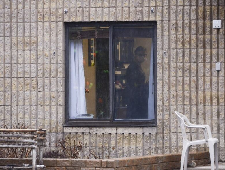 A worker is shown through a window at a long-term care home.