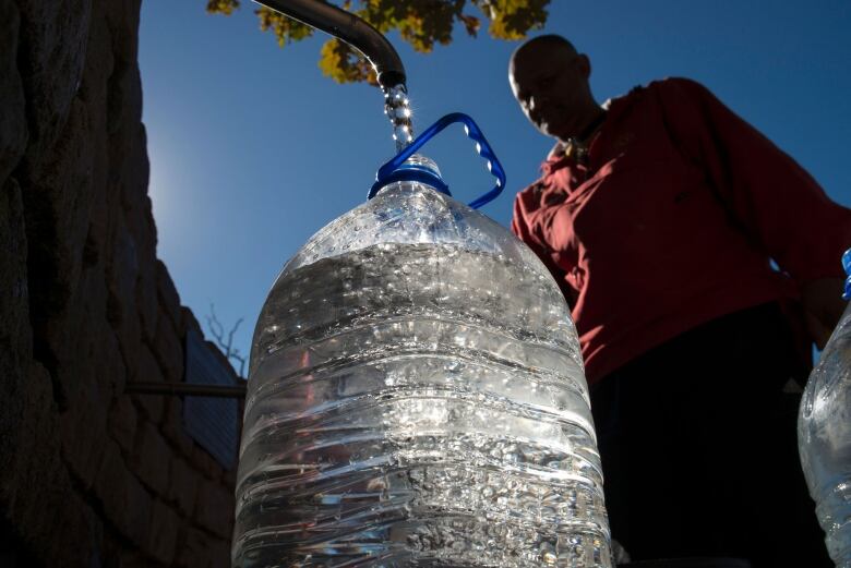 A man fills a large tank of water.