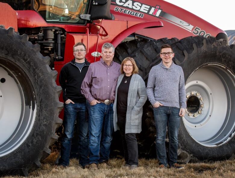 A family stands in front of a tractor.