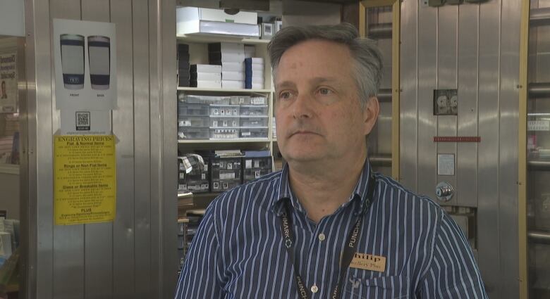 Man in striped shirt stands in front of a vault door. 