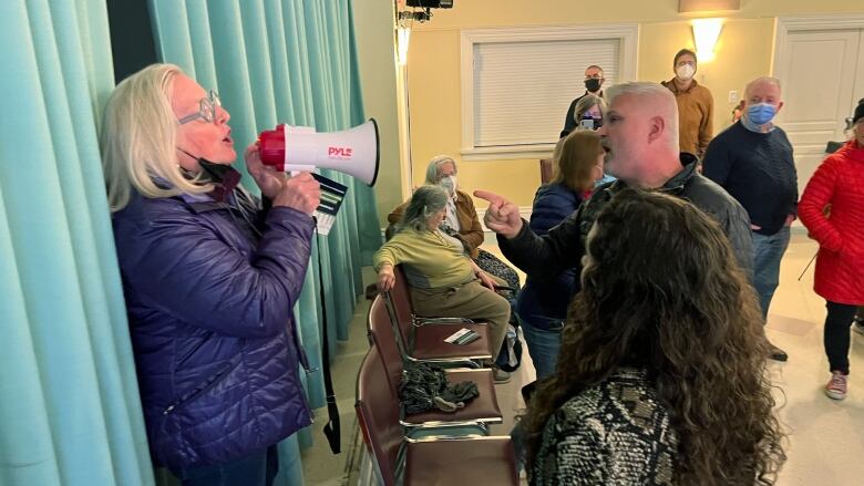 A man points a finger at a woman with a megaphone. 