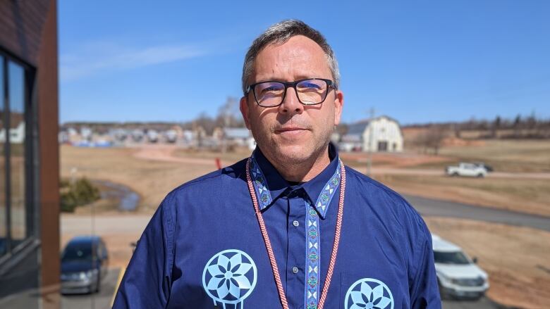 Man in glasses wearing shirt adorned with Mi'kmaw insignia. 