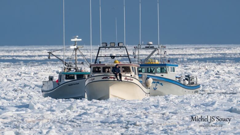 Three fishing boats are shown in the ocean surrounded by chunks of ice.