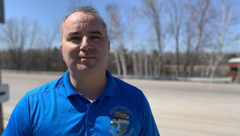 A man in a blue shirt looks at the camera. 