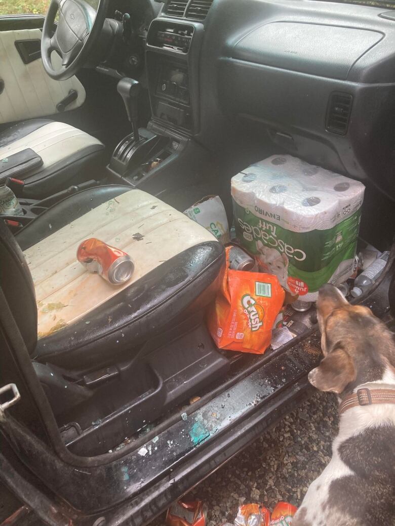 The front passenger seat of a car is destroyed with smashed glass, sticky soda, and empty soda cans. 