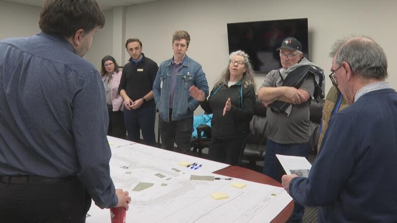 People gathered around maps on table.