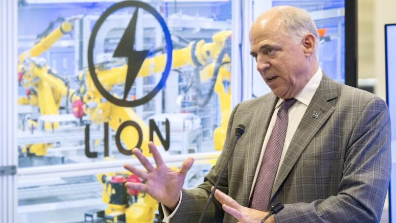 A man speaks at a podium at a battery plant. 