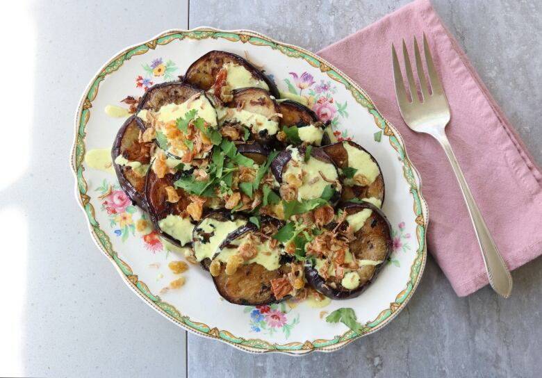 Sliced aubergines on a plate with sauce on top.