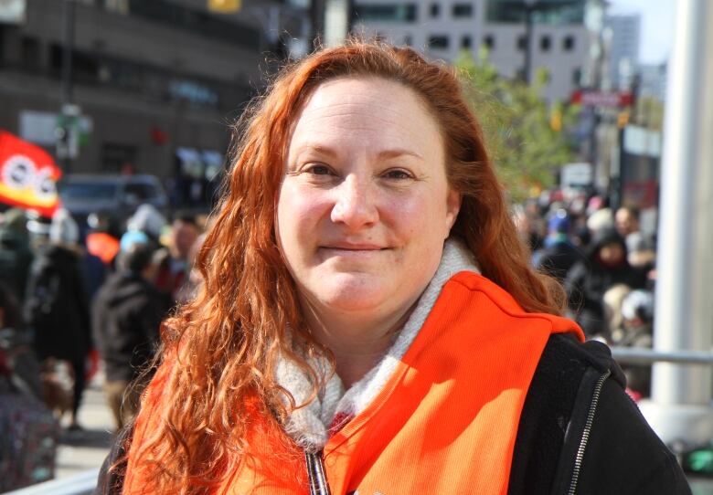 Woman stands outside with crowd in the background