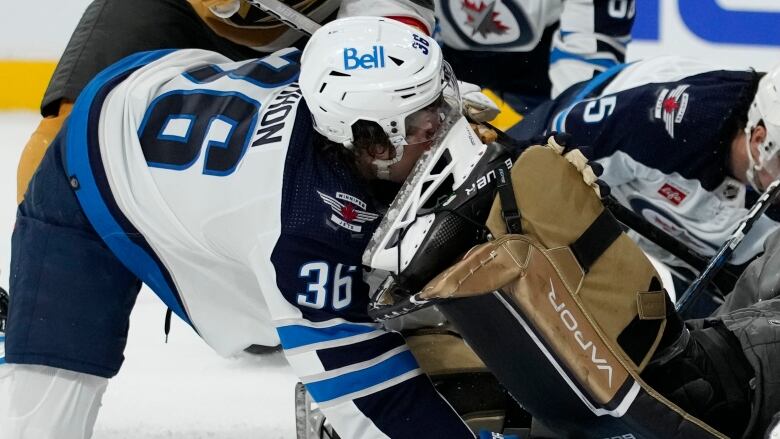 The blade of ahockey skate is seen pushing up under the visor and against the temple of a Winnipeg Jets player.