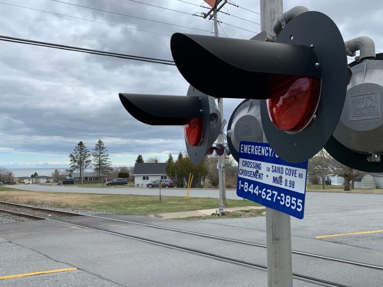 Railway crossing sign at intersection reads Sandy Cove Road. 