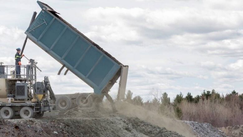 A truck dumping a substance into a dump site. 