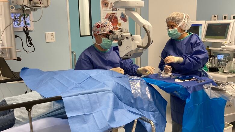 Surgeon performing eye surgery on a patient.