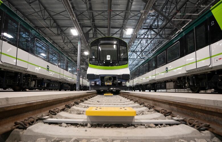 Head on shot from track level of shiny new white-and-green train.