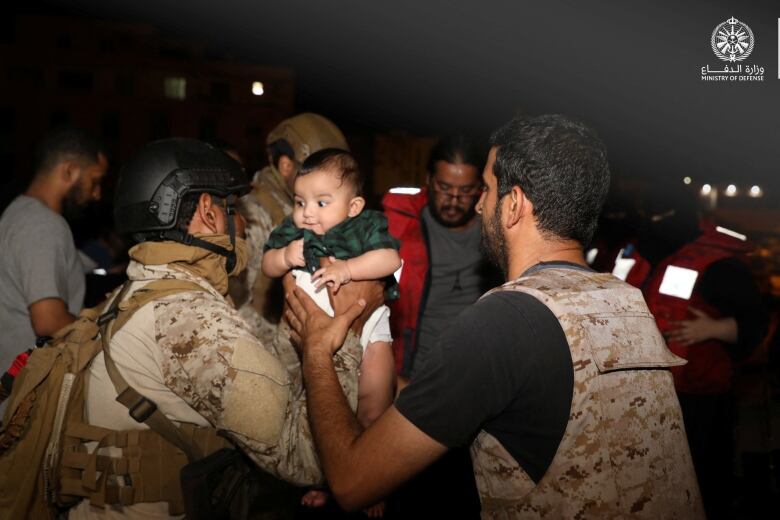 Two rescuers hold a baby.