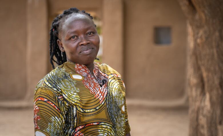 A woman stands in a yard near her home in a refugee camp. 