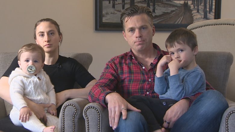 A family sits on couches looking at the camera.