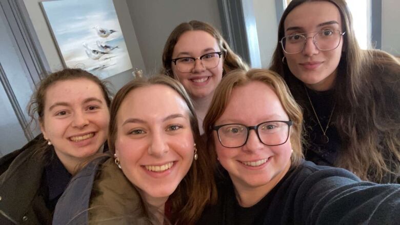 Five nursing students are smiling for a group selfie.