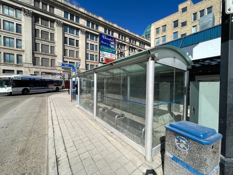 A bus turns down a street next to a bus shelter.