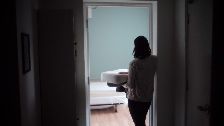 A staff member carries bedding in one of the suites at Toronto's Interval House, an emergency shelter for women in abusive situations, on Feb. 6, 2017.