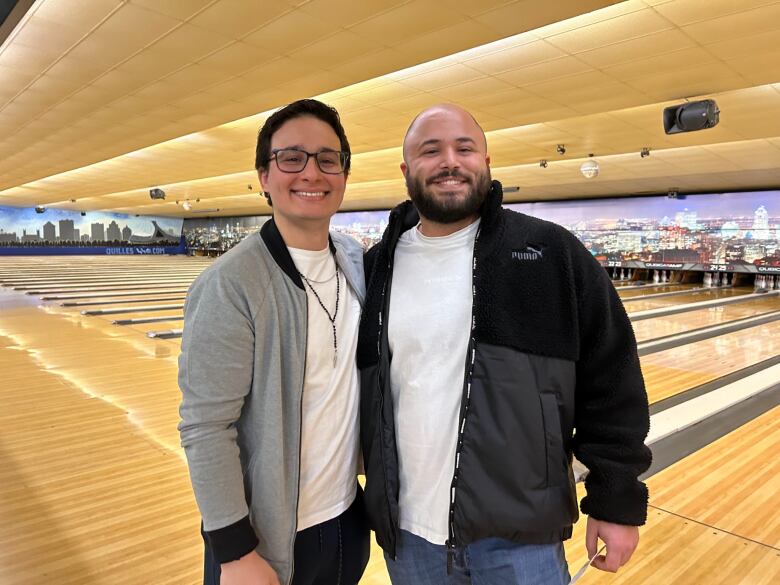 Two men lock arms and smile.