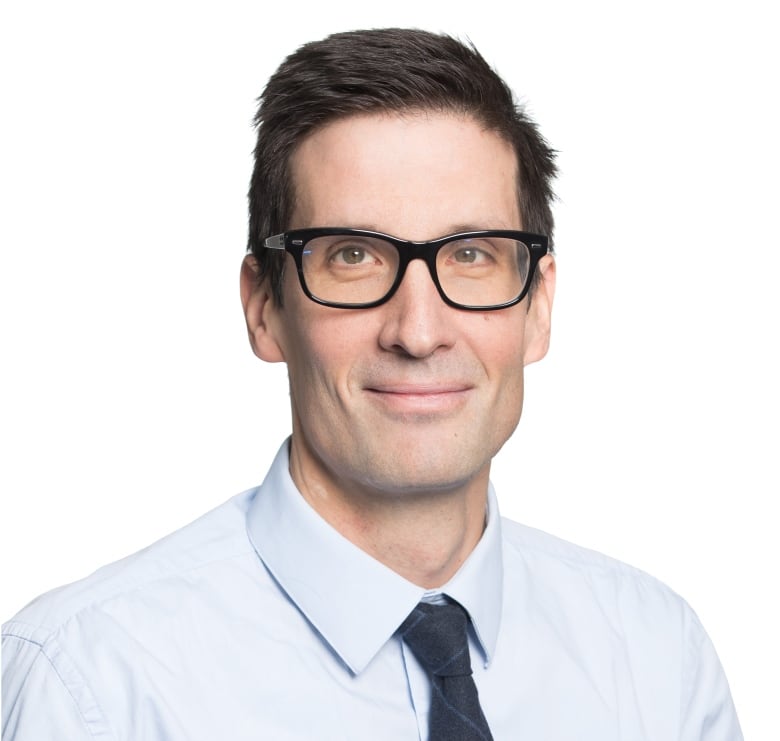 Man wearing a tie and glasses posing for a headshot