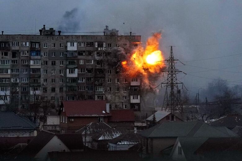 A fiery explosion in the upper floors of an apartment building is shown. 