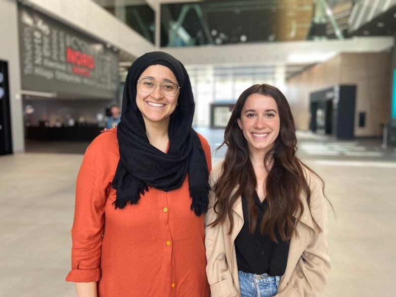 Two women stand together and are smiling for the camera. 